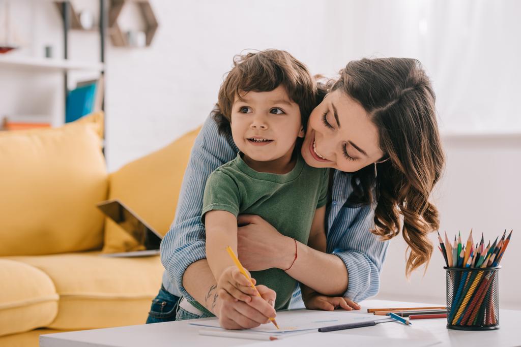 Mãe e filho desenho com lápis de cor na sala de estar
 - Foto, Imagem