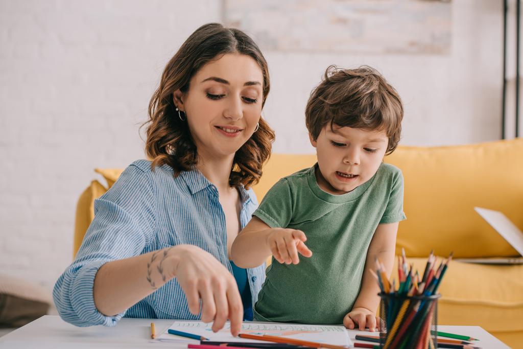 Μητέρα και γιός σχέδιο με χρωματιστά μολύβια στο σαλόνι - Φωτογραφία, εικόνα