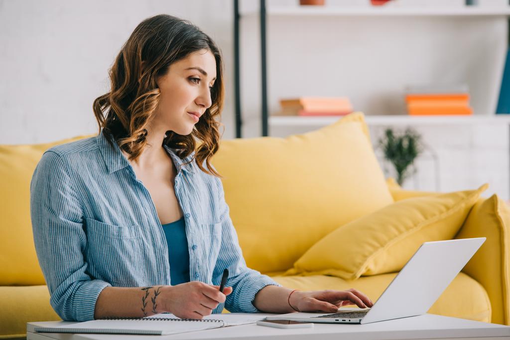 Busy attractive woman working with laptop in living room - Photo, Image