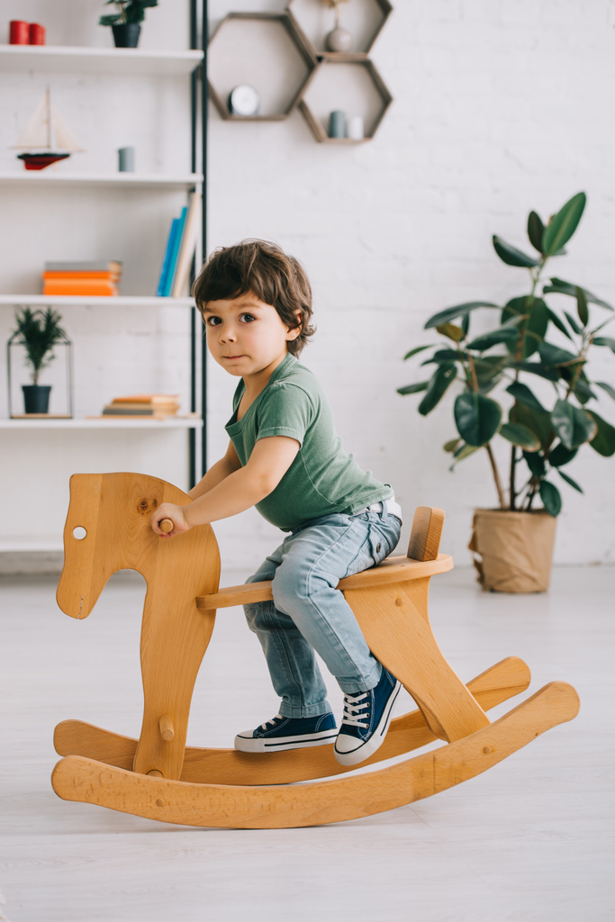 dziecko siedzi na drewnianym konia na biegunach w salonie - Zdjęcie, obraz