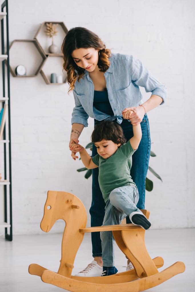 Enfant sur cheval à bascule tenant la main avec maman dans le salon
 - Photo, image