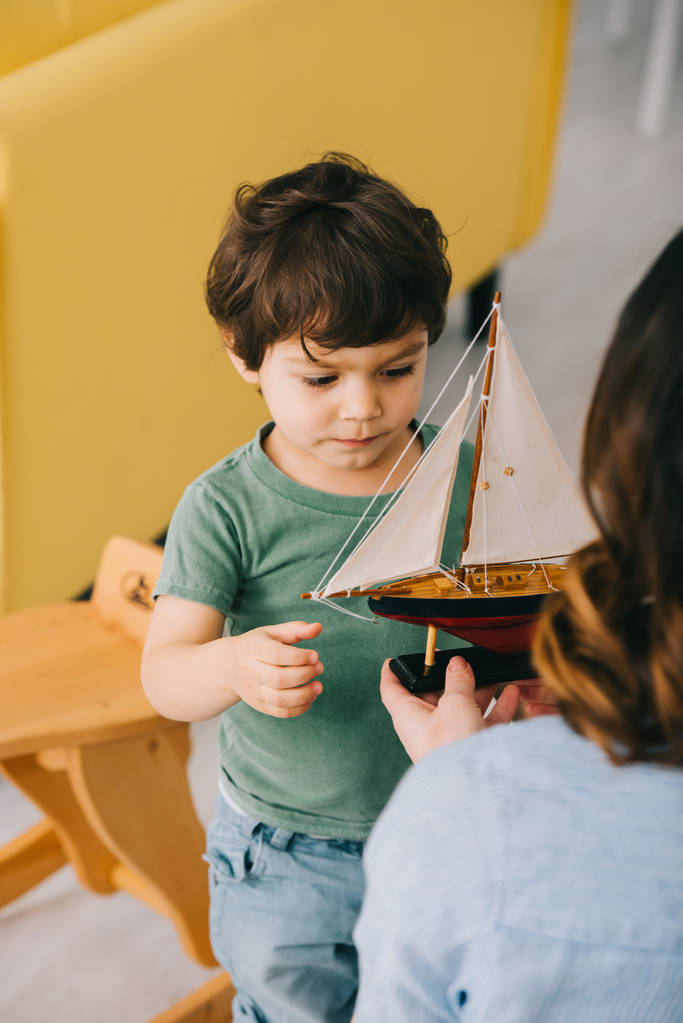 Cropped view of mother and little son with toy ship - Photo, Image