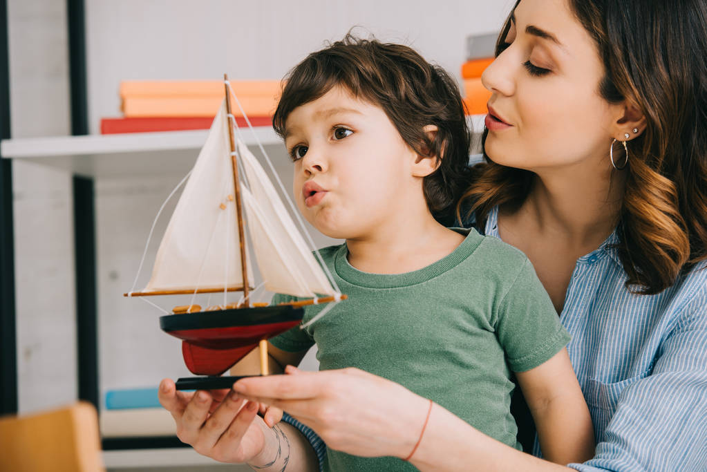 Mutter überrascht Kind mit Spielzeugschiff im Wohnzimmer - Foto, Bild