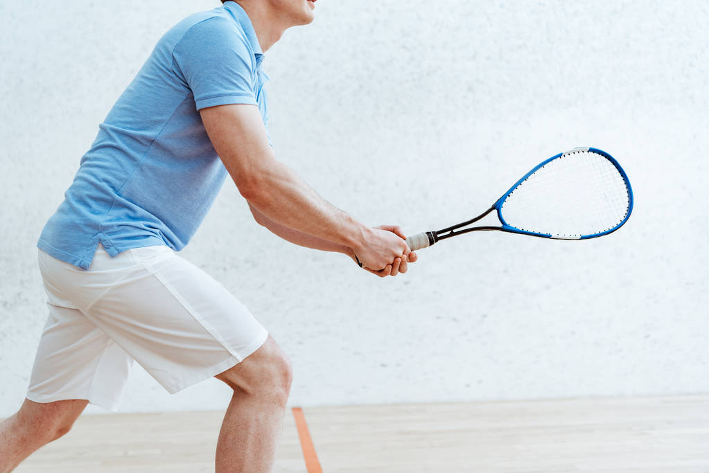 Cropped view of sportsman in blue polo shirt playing squash in sports center - Photo, Image