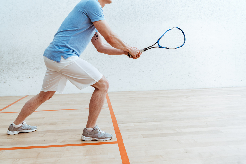 Vista recortada del deportista en polo azul jugando squash en el centro deportivo
 - Foto, Imagen