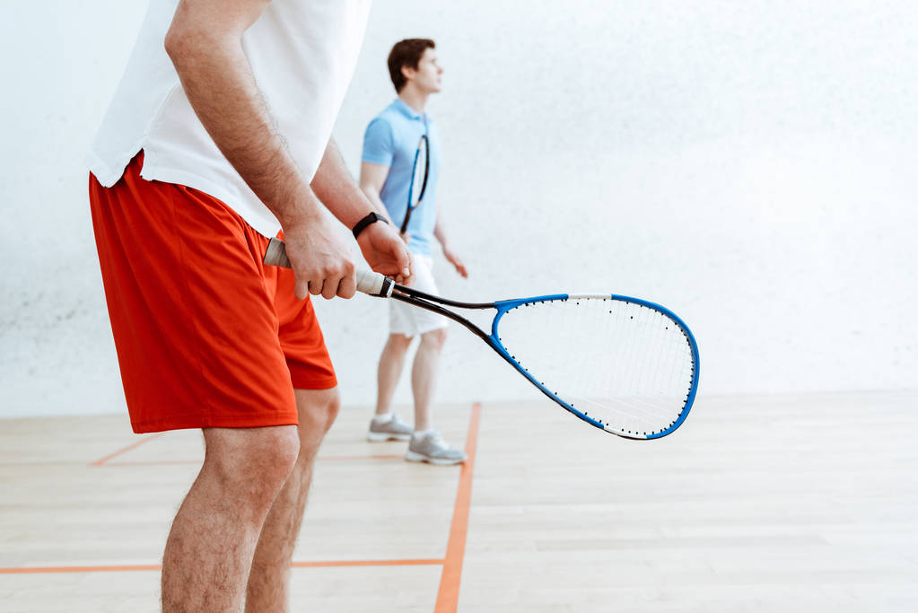 Gedeeltelijke weergave van twee squash spelers met rackets in vierwandige rechtbank - Foto, afbeelding