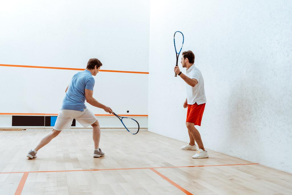 Vista completa de dos deportistas jugando squash en pista de cuatro paredes
 - Foto, imagen