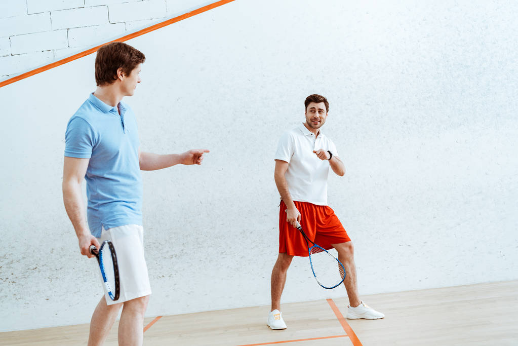 Volledige lengte weergave van squash spelers die naar elkaar kijken en met de vingers wijzen - Foto, afbeelding