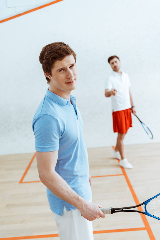 Knappe squash speler in blauwe poloshirt kijken naar camera - Foto, afbeelding