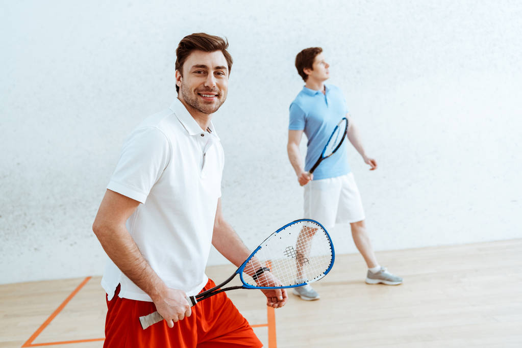 Giocatore di squash barbuto con racchetta guardando la fotocamera con sorriso
 - Foto, immagini