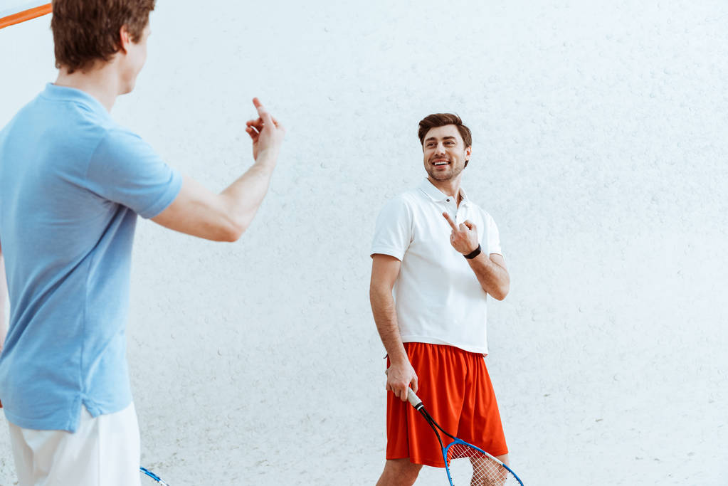 Cropped view of squash players showing middle fingers to each other - Photo, Image