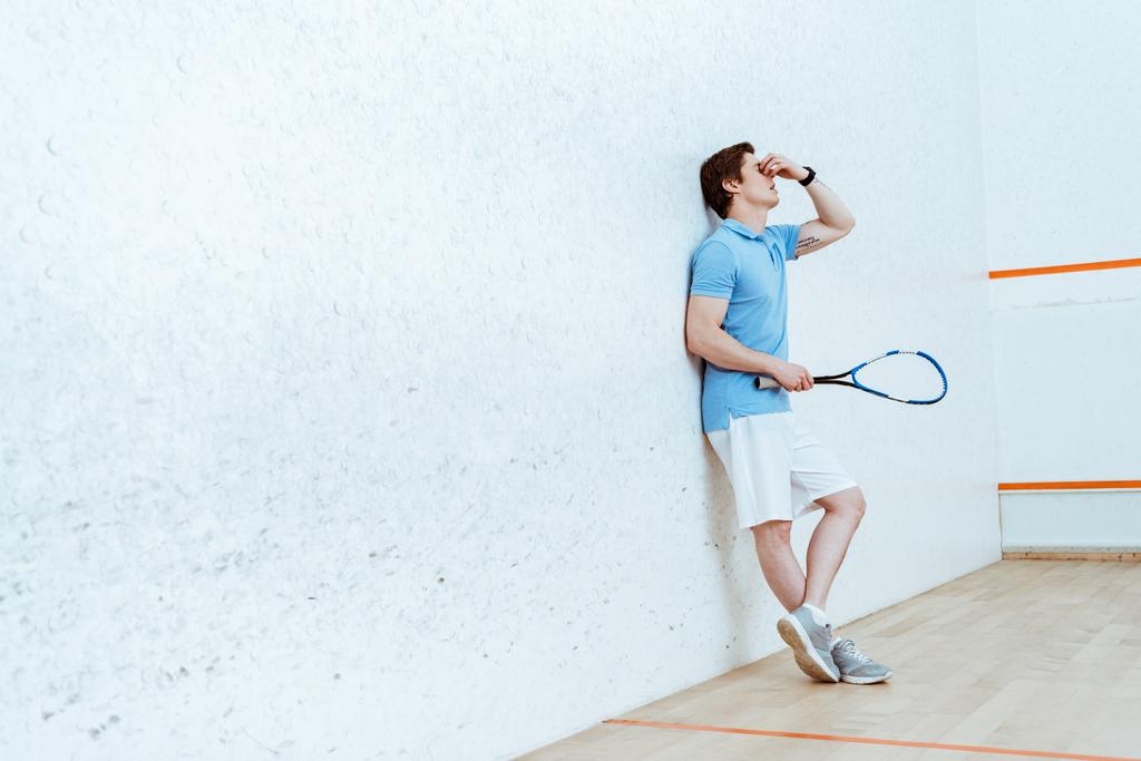 Vue pleine longueur du joueur de squash fatigué touchant les yeux avec la main
 - Photo, image