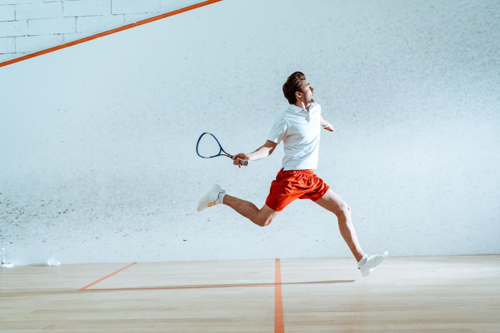 Vue pleine longueur du sportif avec raquette en cours d'exécution tout en jouant au squash
 - Photo, image