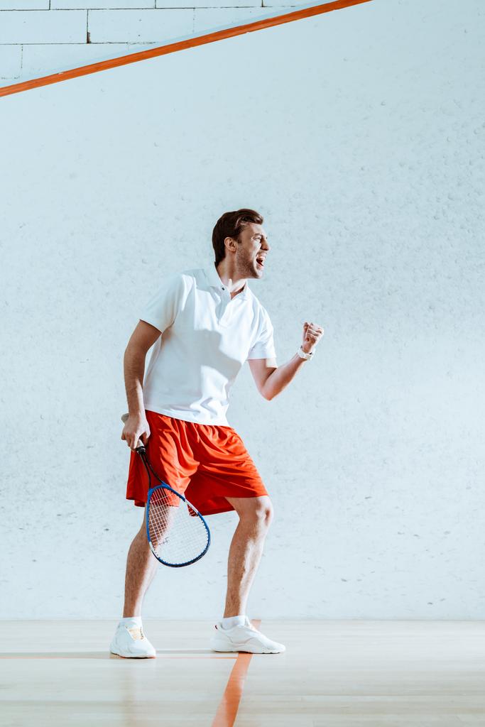 Visualizzazione completa del giocatore di squash felice con racchetta che mostra sì gesto
 - Foto, immagini