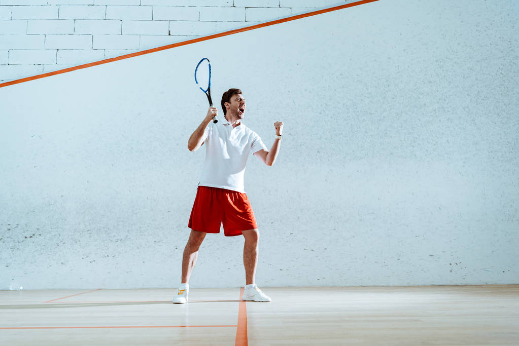 Vue complète du joueur de squash heureux avec raquette montrant un geste oui
 - Photo, image