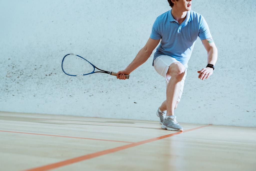 Частичный вид спортсмена в синей рубашке поло, играющего в сквош
 - Фото, изображение