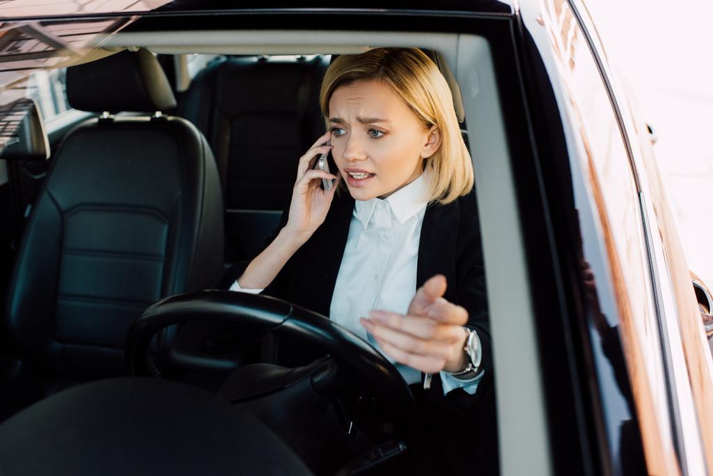 chateado mulher loira falando no smartphone enquanto gestos no carro
  - Foto, Imagem