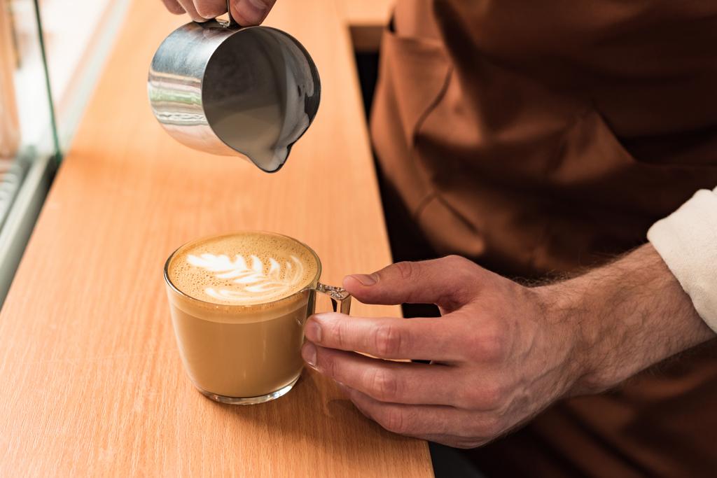 Vista cortada de barista derramando leite no café
 - Foto, Imagem