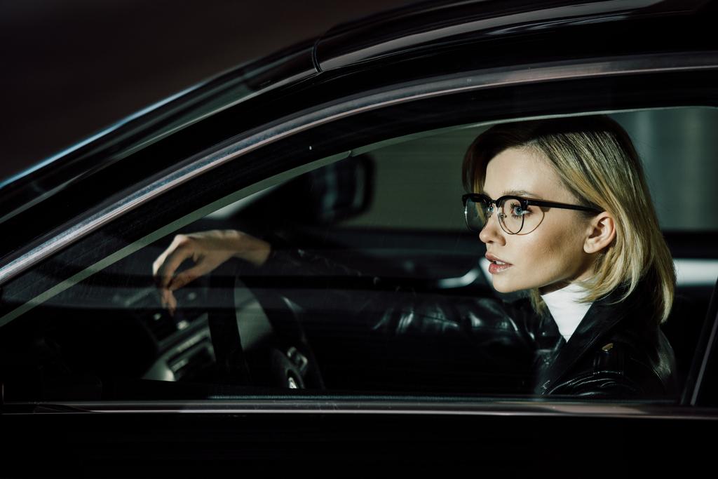 aantrekkelijke blonde vrouw in glazen zitten in de auto  - Foto, afbeelding