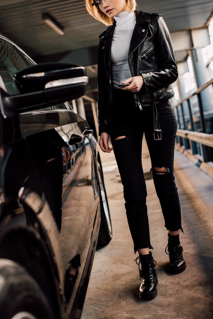обрізаний вид блондинки, що тримає ключ з ключовим ланцюгом біля чорного автомобіля
  - Фото, зображення