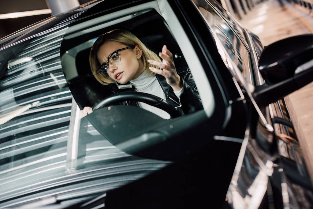 stressed blonde girl in glasses talking on smartphone in car  - Photo, Image