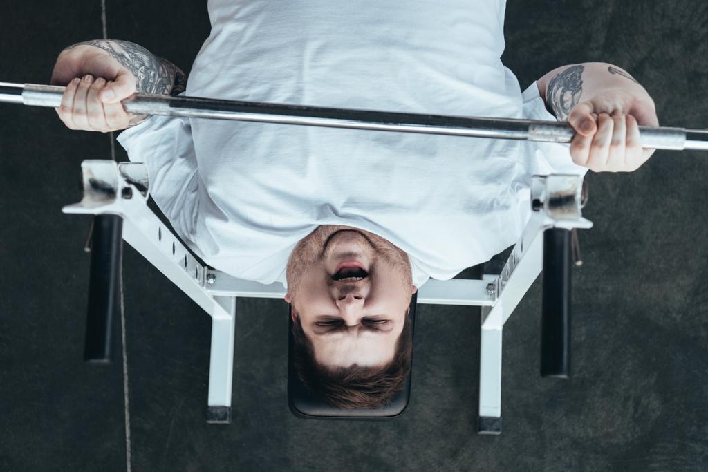 nejvyšší pohled na Tetovaný muž s nadváhou trénink s barbellem v tělocvičně - Fotografie, Obrázek