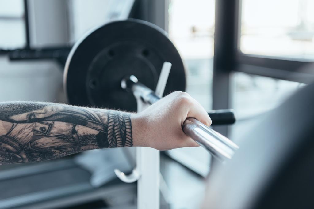 ostříhané zobrazení tetovaného muže cvičujícího v sportovní centrice - Fotografie, Obrázek