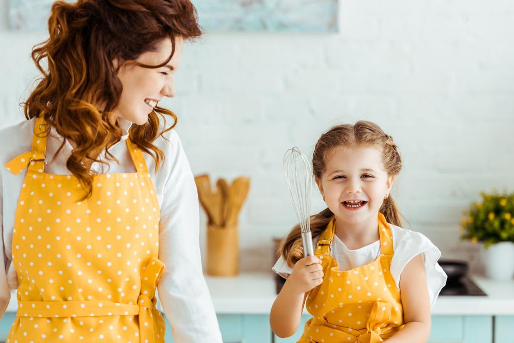 mutfakta balon çırpma ile mutlu kızı bakarak gülümseyen anne - Fotoğraf, Görsel