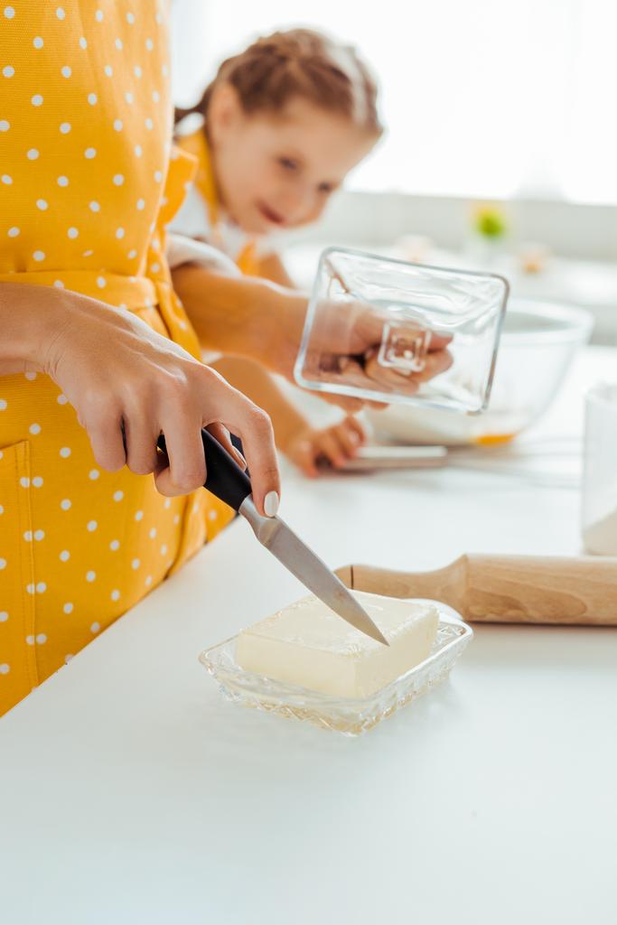 Frau schneidet mit Messer nahe Tochter Butter - Foto, Bild