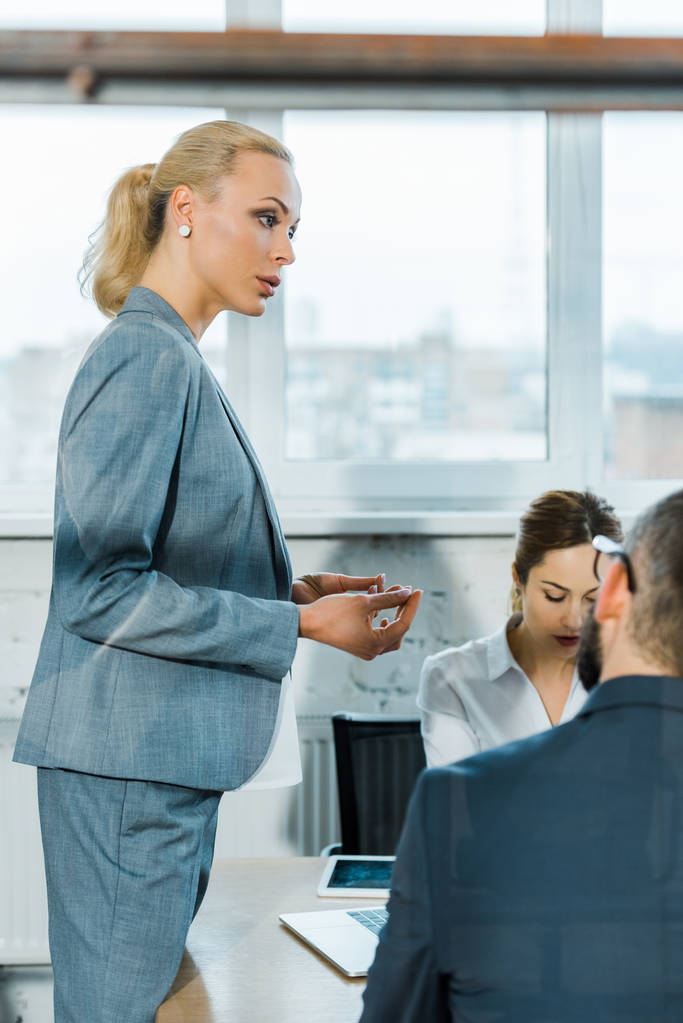 селективный фокус привлекательного блондинистого бизнес-тренера, стоящего рядом с сотрудниками в конференц-зале
  - Фото, изображение