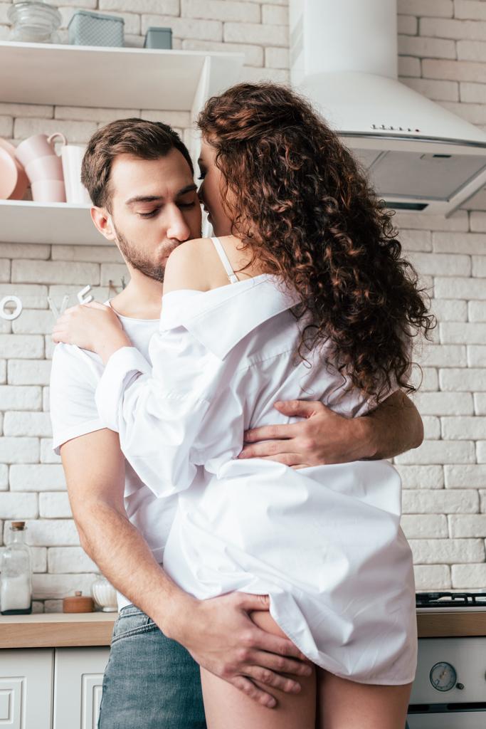 adam seksi kız arkadaşı kucaklayan ve mutfakta omuz onu öpme - Fotoğraf, Görsel
