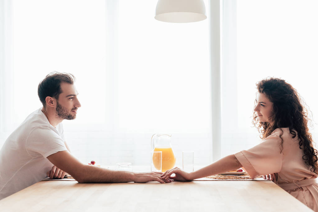 couple toucher les mains et regarder l'autre à la table pendant le petit déjeuner
 - Photo, image