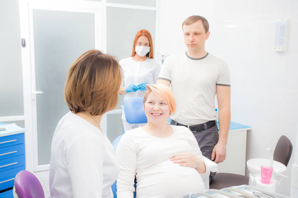 terhes nő a recepción a fogorvos, a férj jelen van az irodában. Fogápolás terhes nőknek - Fotó, kép