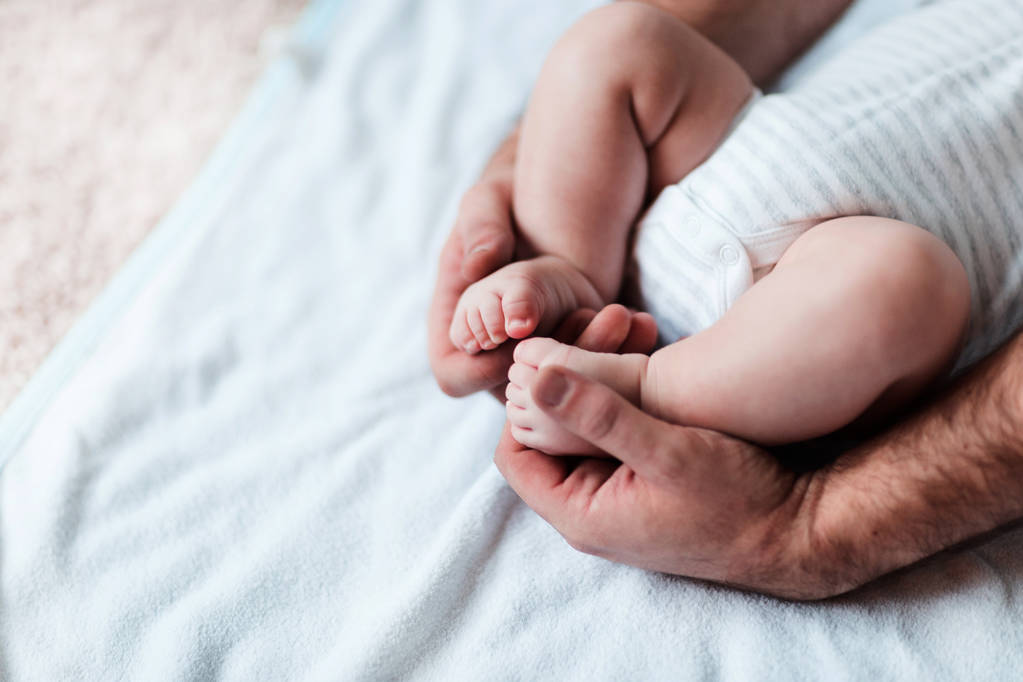 Mães mãos cuidadosamente mantendo bebês pé com ternura
 - Foto, Imagem