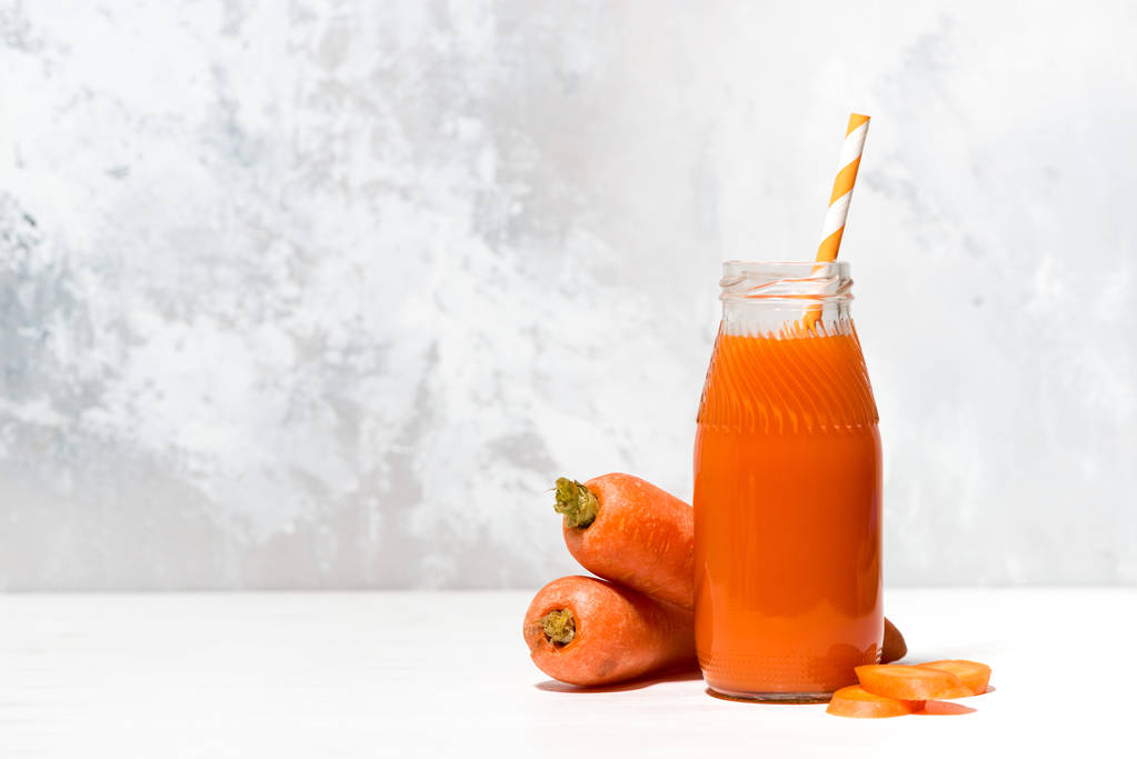 jugo de zanahoria fresca en una botella sobre fondo blanco
 - Foto, imagen