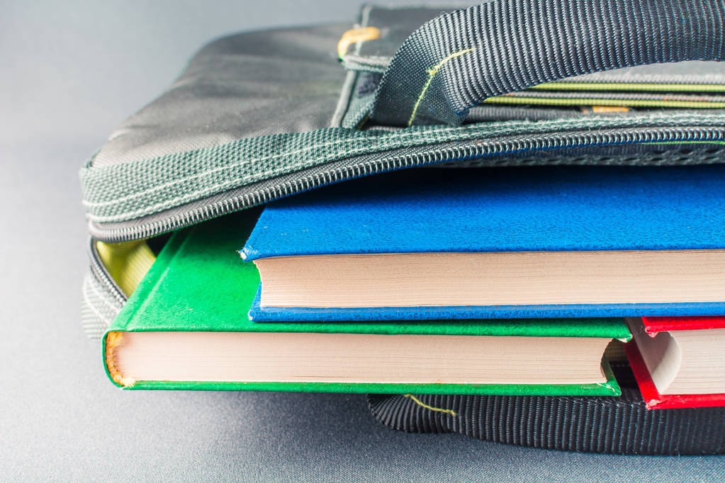 Куча разноцветных книг лежит в сумке для ноутбука
 - Фото, изображение