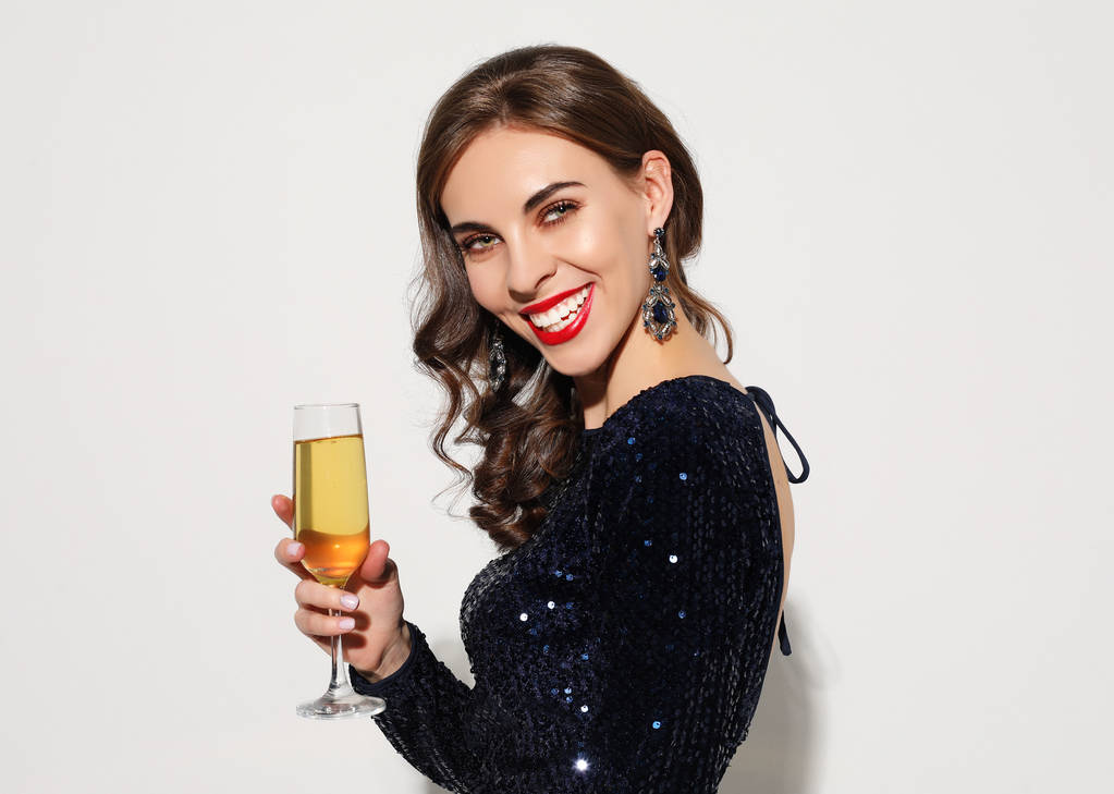 schöne Mädchen in einem Cocktailkleid mit Abend-Make-up und Locken hält ein Glas Champagner - Foto, Bild
