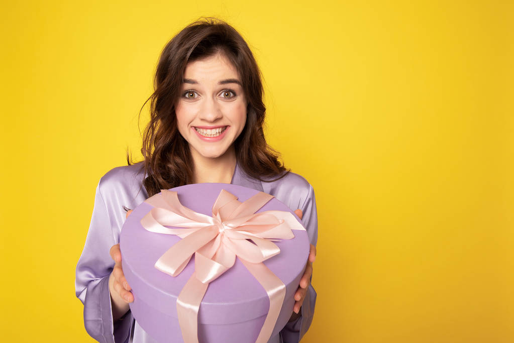 Веселая красивая девушка держит праздничный подарок
 - Фото, изображение