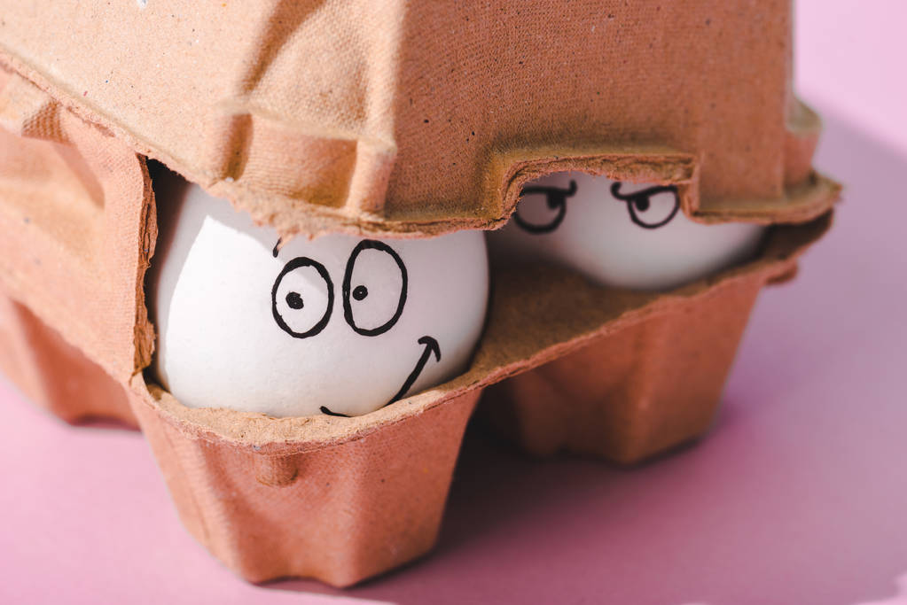 卵のカートンで怒りと笑顔の表情で卵を閉じる - 写真・画像