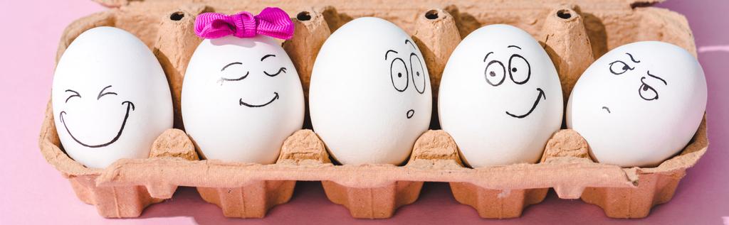 panoramic shot of eggs with different face expressions in egg carton on pink - Photo, Image
