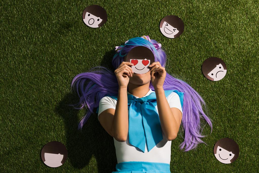 Anime meisje in paarse pruik liggend op gras met emoticons - Foto, afbeelding