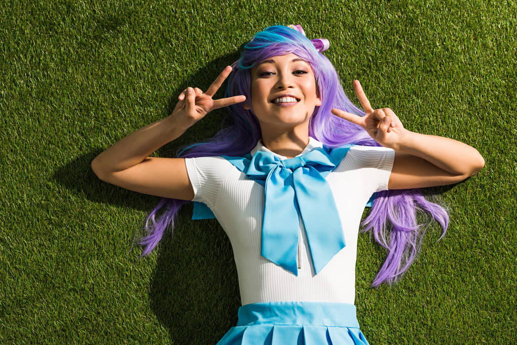 Uśmiechnięta Azjatycka Dziewczyna Anime leżącego na trawie i pokazując znaki pokoju - Zdjęcie, obraz