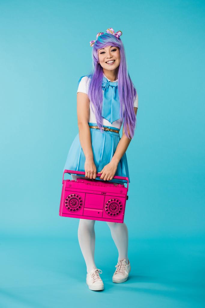 Full length view of asian anime girl holding pink boombox on blue - Photo, Image