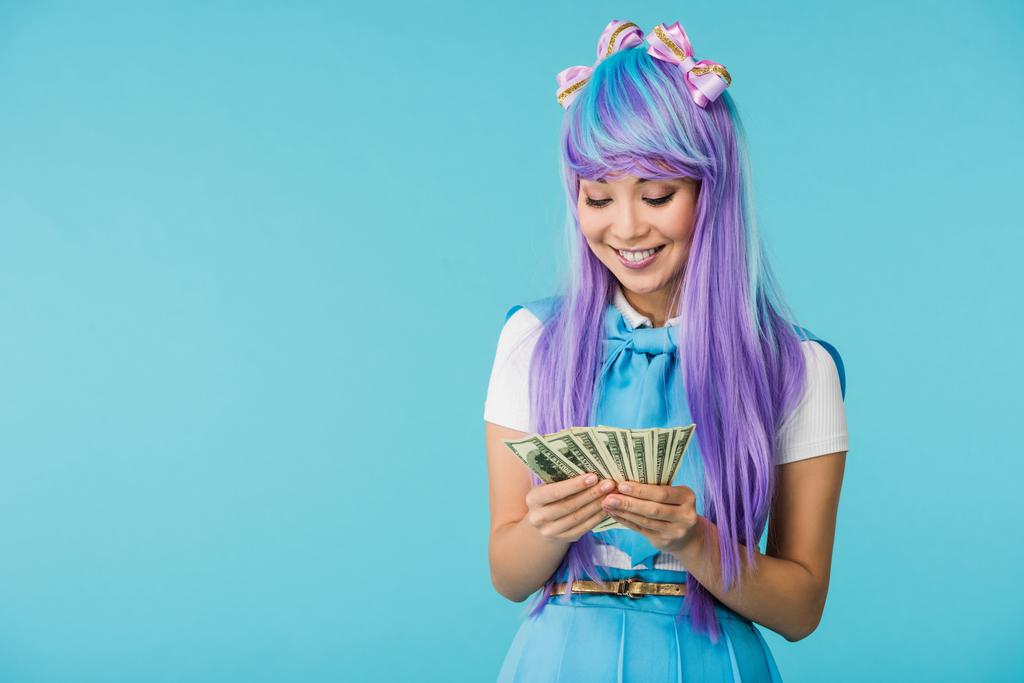 Chica anime asiática en peluca púrpura contando billetes de dólar aislados en azul
 - Foto, Imagen