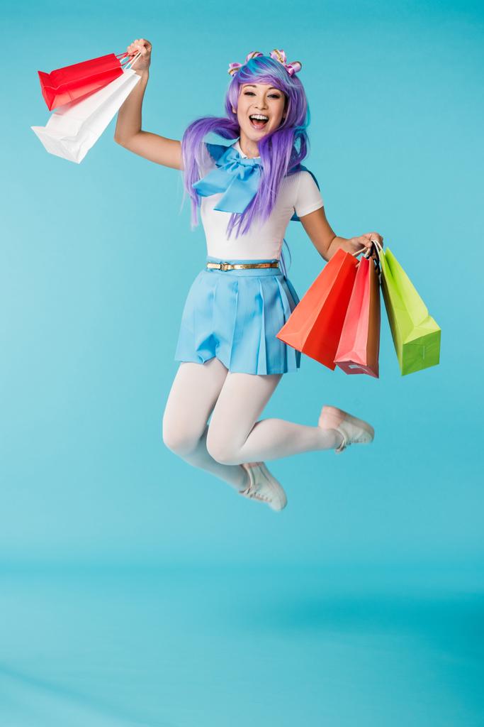 Захоплена азіатська аніме дівчина в перуці стрибає з сумками на синьому
 - Фото, зображення