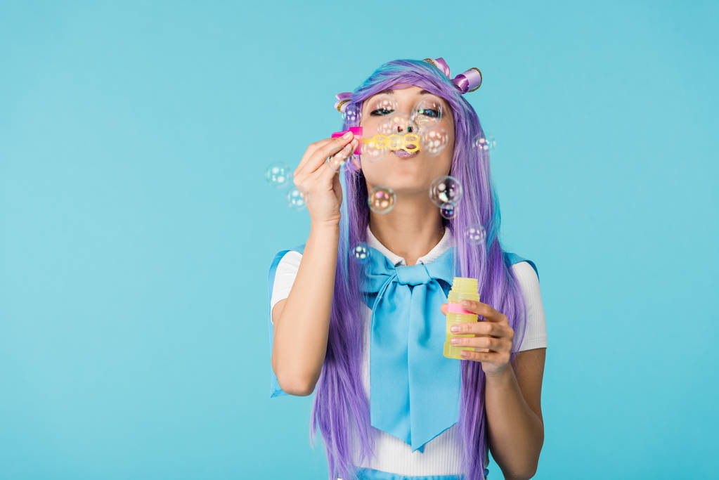 Chica anime asiático en peluca púrpura con burbujas de jabón aislado en azul
 - Foto, Imagen