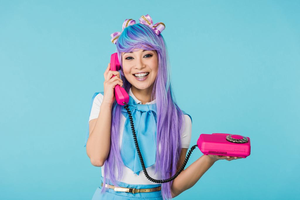 усміхнена азіатська аніме дівчина розмовляє по телефону ізольовано на синьому
 - Фото, зображення