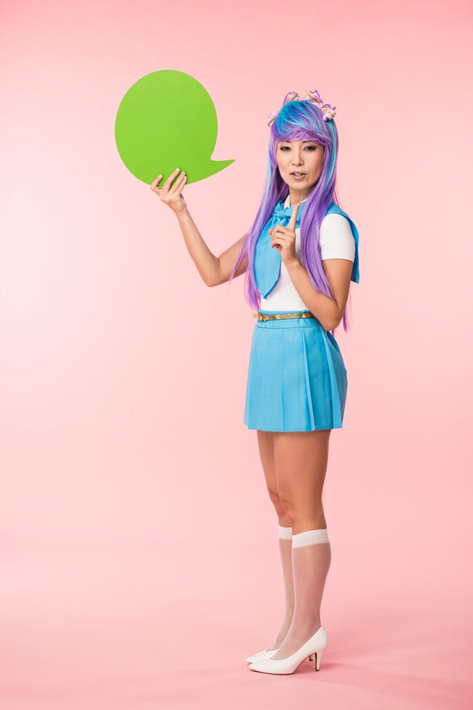 Pełny widok długości azjatyckiego Anime Dziewczyna trzyma zieloną mowę bańki i pokazując pomysł znak na różowy - Zdjęcie, obraz