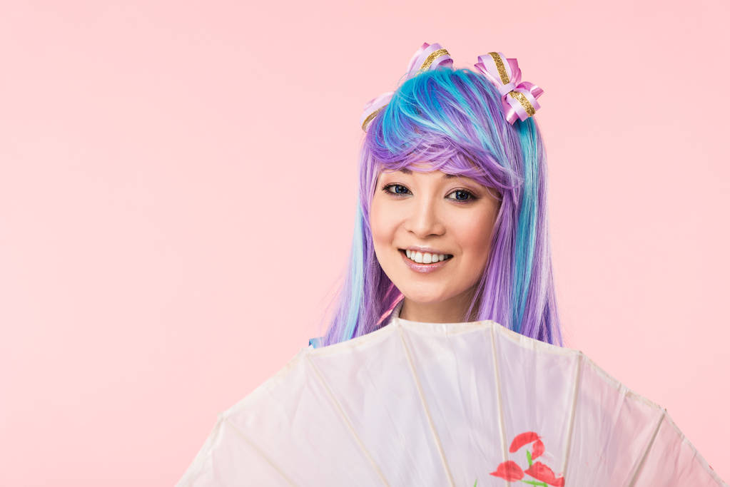 Ázsiai anime lány mosolyogva gazdaság papír esernyő izolált rózsaszín - Fotó, kép