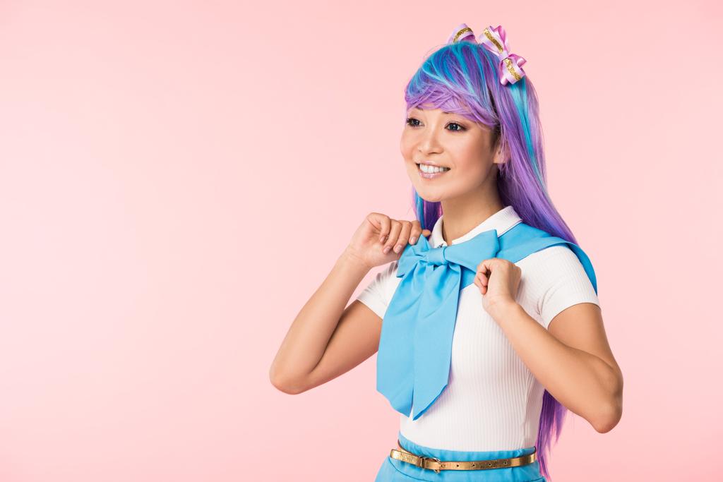 Sonriente chica otaku en peluca púrpura mirando hacia otro lado aislado en rosa
 - Foto, imagen